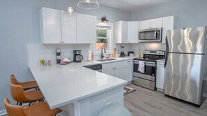 A modern kitchen with white cabinets, stainless steel appliances, and pendant lighting. - Delightfully Renovated 4 BR 2 BA Near DT Riverwalk (San Antonio)