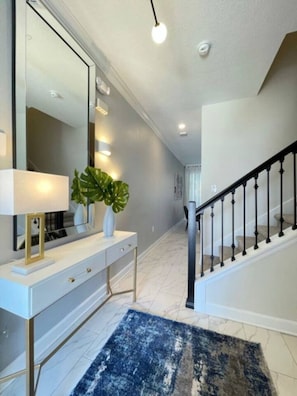 A hallway with a white console table, a large mirror, and a potted plant. - Amazing Championsgate w Pool, Water Park, BBQ (Davenport)