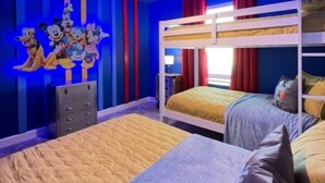Una habitación con literas, un aparador y una pared decorada con personajes de dibujos animados.