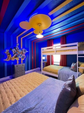 A room with bunk beds, a dresser, and a wall with cartoon characters.