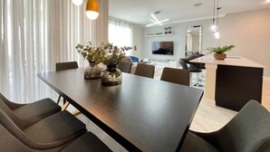 Un comedor moderno con una mesa larga, sillas, luces colgantes y un florero con flores.