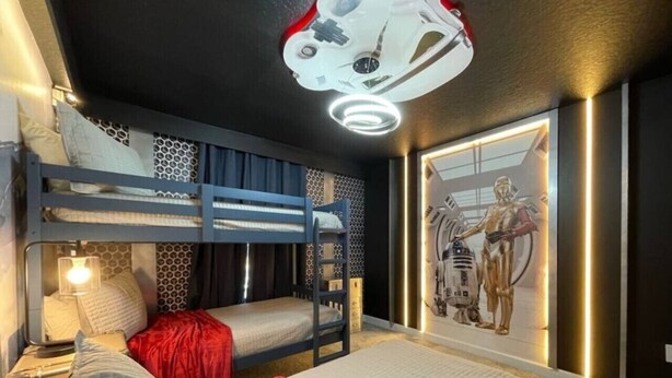 Habitación con literas, decoración mural temática de Star Wars y una lámpara de techo.