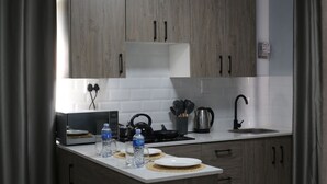 A modern kitchen with wooden cabinets, a white countertop, a kettle, a water bottle, and a sink.