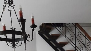 A living room with a staircase, a chandelier, a television, a guitar, and a framed painting. - Ai Canarbin  (Lerici)