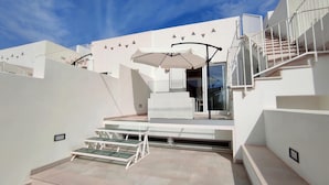 A modern outdoor area with a glass table, a white sofa, and an umbrella. - Le Sorelle del Mare - Sole a 450m Dalla Spiaggia (Salve)
