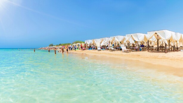 A beach with clear turquoise water, rows of white tents, and a sandy shore. - Le Sorelle del Mare - Sole a 450m Dalla Spiaggia (Salve)