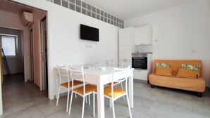 A compact living space with a dining area, kitchenette, and a sofa. - Le Sorelle del Mare - Sole a 450m Dalla Spiaggia (Salve)