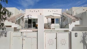 A modern building with a symmetrical design, featuring a central staircase, a covered outdoor seating area, and a gated entrance with decorative sun motifs. - Le Sorelle del Mare - Sole a 450m Dalla Spiaggia (Salve)