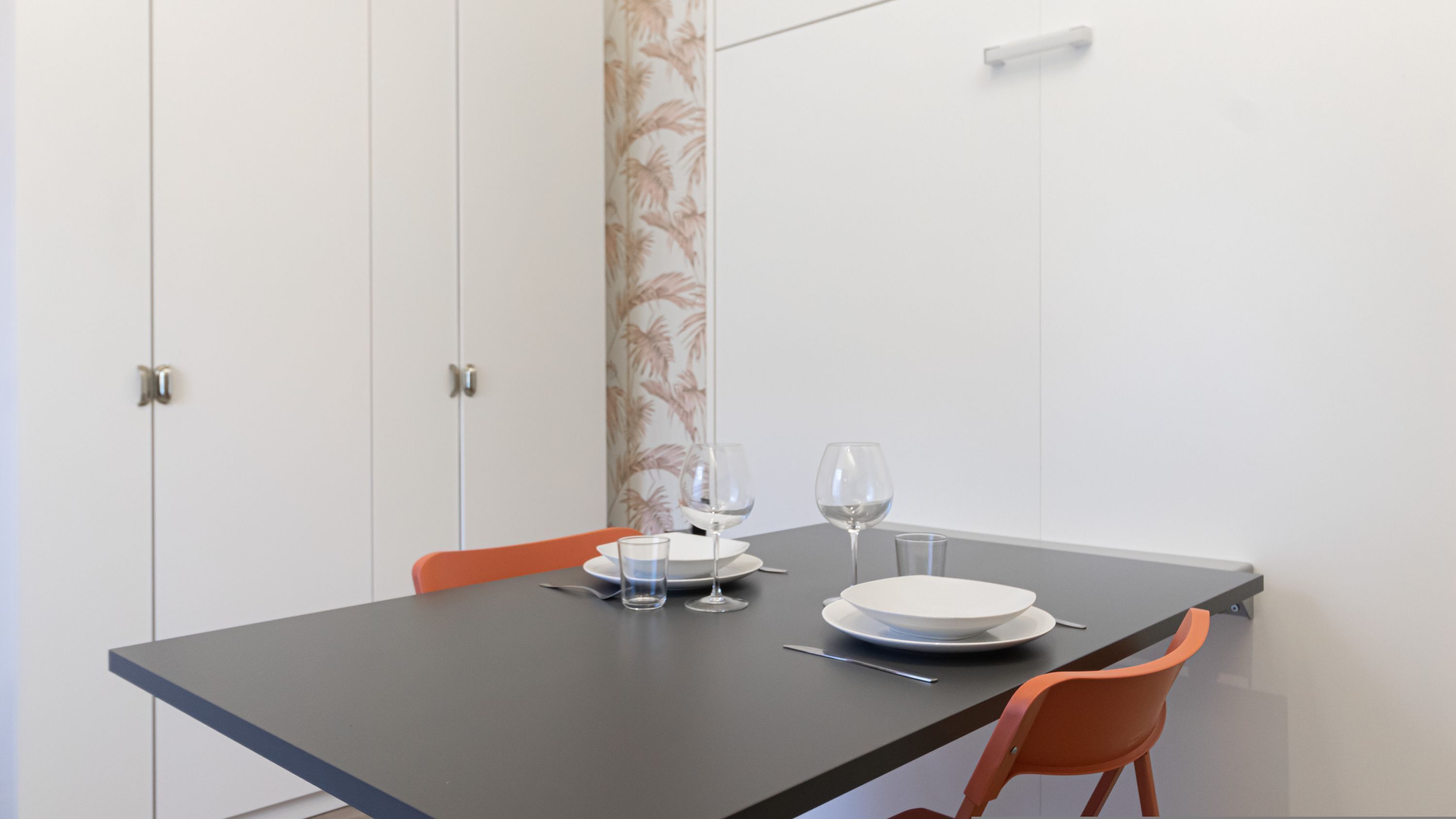 Een eettafel met twee stoelen, een bord, twee wijnglazen en een klein glas.