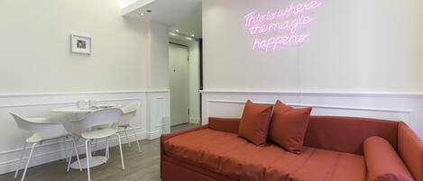 Una habitación moderna con un sofá rojo, sillas blancas y un letrero de neón en la pared.