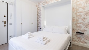 A hotel room with a bed, a wardrobe, and a bathroom.