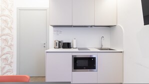 Una cuina compacta amb microones integrat, bullidor, torradora i rentatalls.