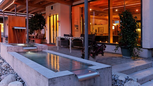 Zona de piscina exterior amb disseny modern, que inclou una piscina rectangular, zona de seients i plantes en testos.