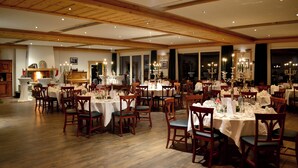 Un restaurant amb diverses taules i caires, terres de fusta i un sostre alt amb bigues al descobert.