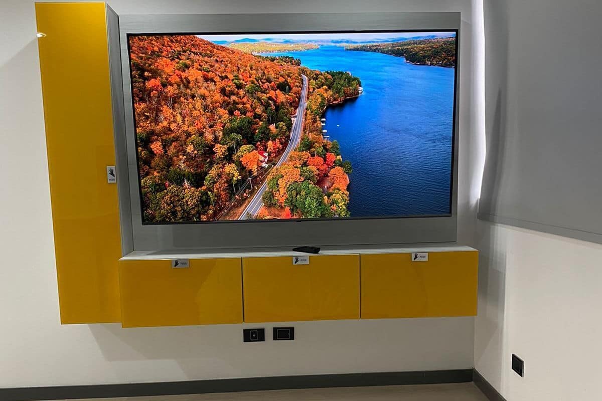 Ein modernes Hotelzimmer mit einem großen Flachbildfernseher an der Wand, einem Bett mit weißer Bettwäsche und einem Holzboden.