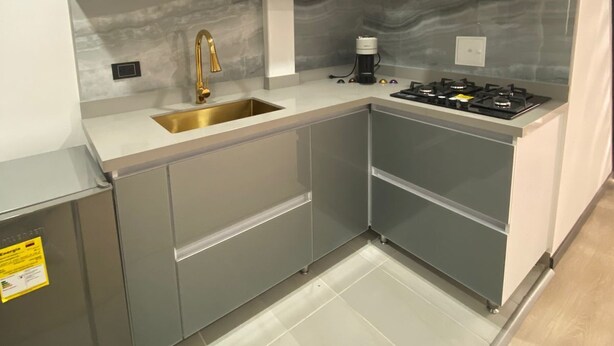 Una cocina moderna con gabinetes grises, un lavamanos de acero inoxidable y una estufa a gas.