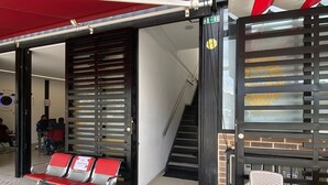 Un espacio de estar al aire libre cubierto con un toldo rojo, una escalera y una silla.