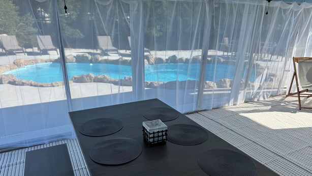 A room with a view of a pool, a table with placemats, and a chair. - Northern Point of Treasure Island, NPR - waterfront w/ pool, sunroom & kayaks! (New Port Richey)