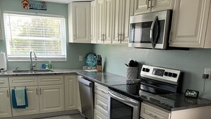 A kitchen with white cabinets, a stainless steel stove, a microwave, and a sink. - Northern Point of Treasure Island, NPR - waterfront w/ pool, sunroom & kayaks! (New Port Richey)