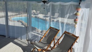 A room with a ceiling fan, a pool view, and two lounge chairs. - Northern Point of Treasure Island, NPR - waterfront w/ pool, sunroom & kayaks! (New Port Richey)