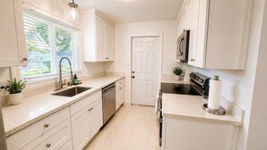 A kitchen with white cabinets, a stainless steel sink, a dishwasher, a stove, and a microwave. - Spacious 3BR Home - Near Downtown Martinez (Martinez)