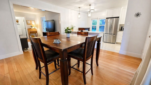 A modern kitchen with a dining area, wooden flooring, and stainless steel appliances.