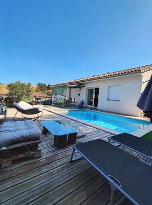 Una piscina con sillas de descanso y una terraza de madera.
