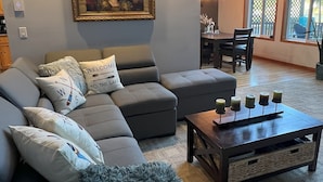 A living room with a sectional sofa, a coffee table with candles, and a painting on the wall. - Beautiful lakefront Casa del Lago on Lake Roesiger (Snohomish)