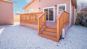 Une maison de plain-pied dotée d’une terrasse en bois et d’un escalier menant à la porte d’entrée.