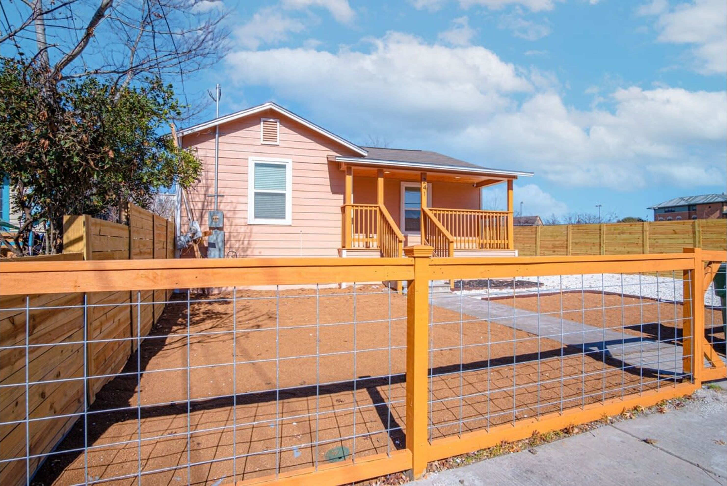 A single-story house with a porch and a fenced backyard.