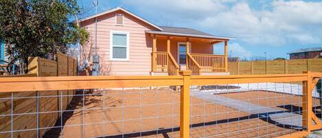 A single-story house with a porch and a fenced backyard.