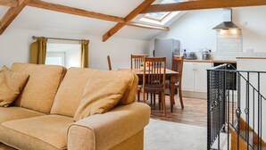 A cozy loft-style room with a wooden ceiling, a sofa, a dining table with chairs, and a kitchen area with a refrigerator and a stove. - 2 bedroom accommodation in Ruthwell, near Annan (Ruthwell, near Annan)