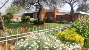 A residential building with a brick facade, surrounded by a well-maintained garden with various plants and flowers. - savanna guest house (Bulawayo)
