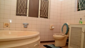 A bathroom with a bathtub, toilet, and a window with bars. - savanna guest house (Bulawayo)