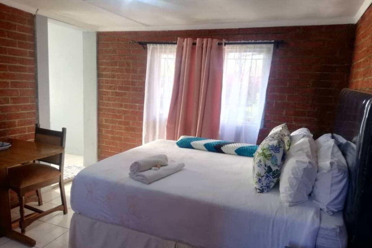 A room with a bed, a desk, and a window with curtains.