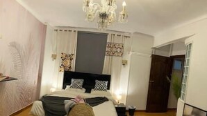 Un dormitorio con cama, candelabro, cortinas y una puerta.