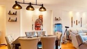 Un comedor con una mesa y sillas, un tapete estampado e iluminación colgante.