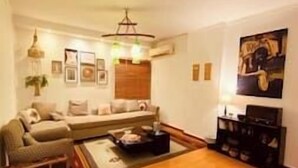 Una sala de estar con piso de madera, un conjunto de sofá, una mesa de centro y un cuadro en la pared.