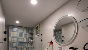 Ein modernes Badezimmer mit Duschkabine aus Glas, rundem Spiegel und Holzwaschtisch.