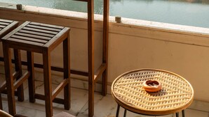 Ein Balkon mit Tisch, Stühlen und Blick auf eine Stadtlandschaft und einen Fluss.