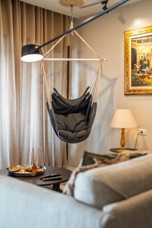 A room with a hanging chair, a lamp, a painting, and a sofa. - The Nile Vintage Haven (Al Gabalayah)