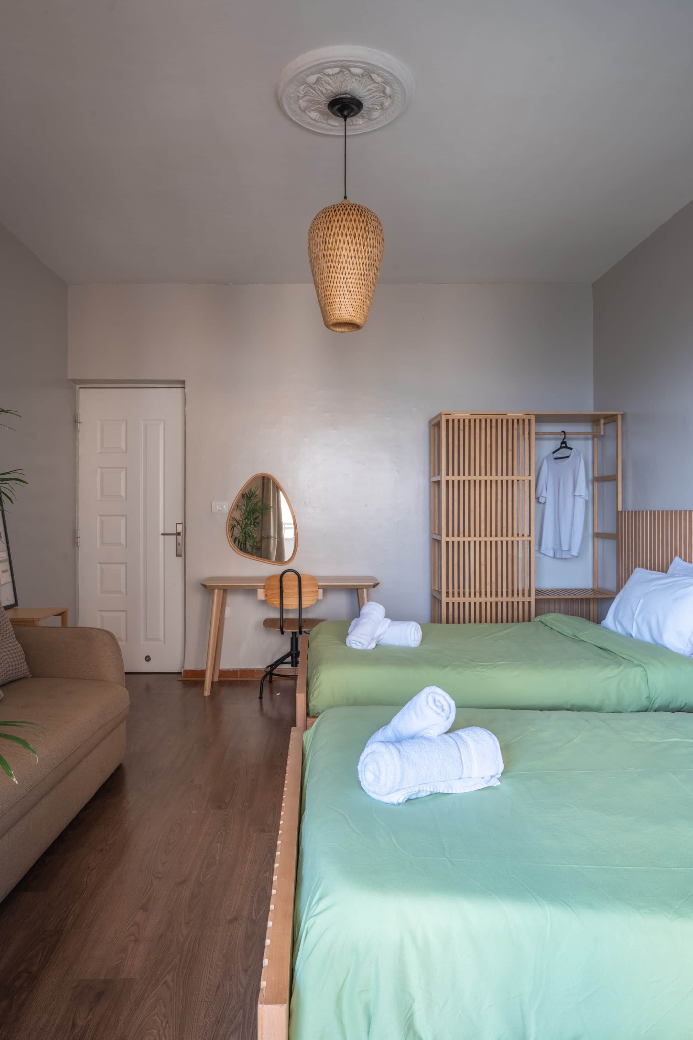 Ein Schlafzimmer mit zwei Betten, einem Holztisch, einem Spiegel und einem Kleiderhaken.