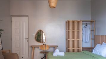 Ein Schlafzimmer mit zwei Betten, einem Holztisch, einem Spiegel und einem Kleiderhaken.