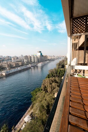 A balcony with a view of a river, city buildings, and a bridge. - The Nile Vintage Haven (Al Gabalayah)
