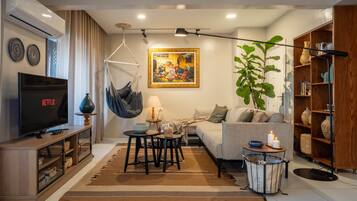 Una sala de estar con sofá, televisión, sillón colgante, mesa y estantería.