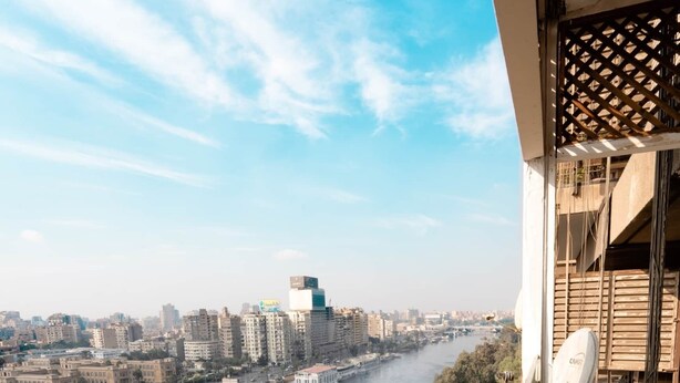 Uma varanda com vista para um rio, edifícios da cidade e uma ponte.