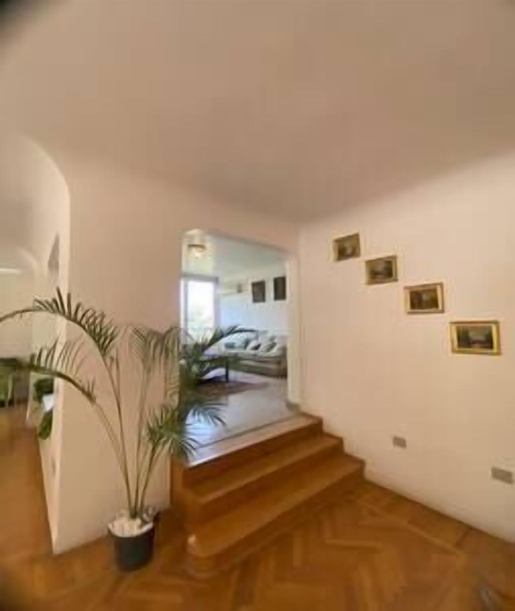 Eine Treppe führt zu einem Schlafzimmer mit einem Bett, einer Topfpflanze und gerahmten Bildern an der Wand.