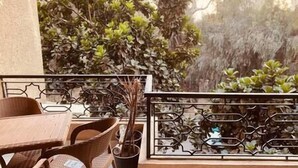 Ein Balkon mit Korbmöbeln, einem Metallgeländer und Topfpflanzen.