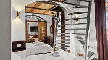 Habitación de hotel con dos camas, techo de madera, escalera de caracol y vistas al exterior.