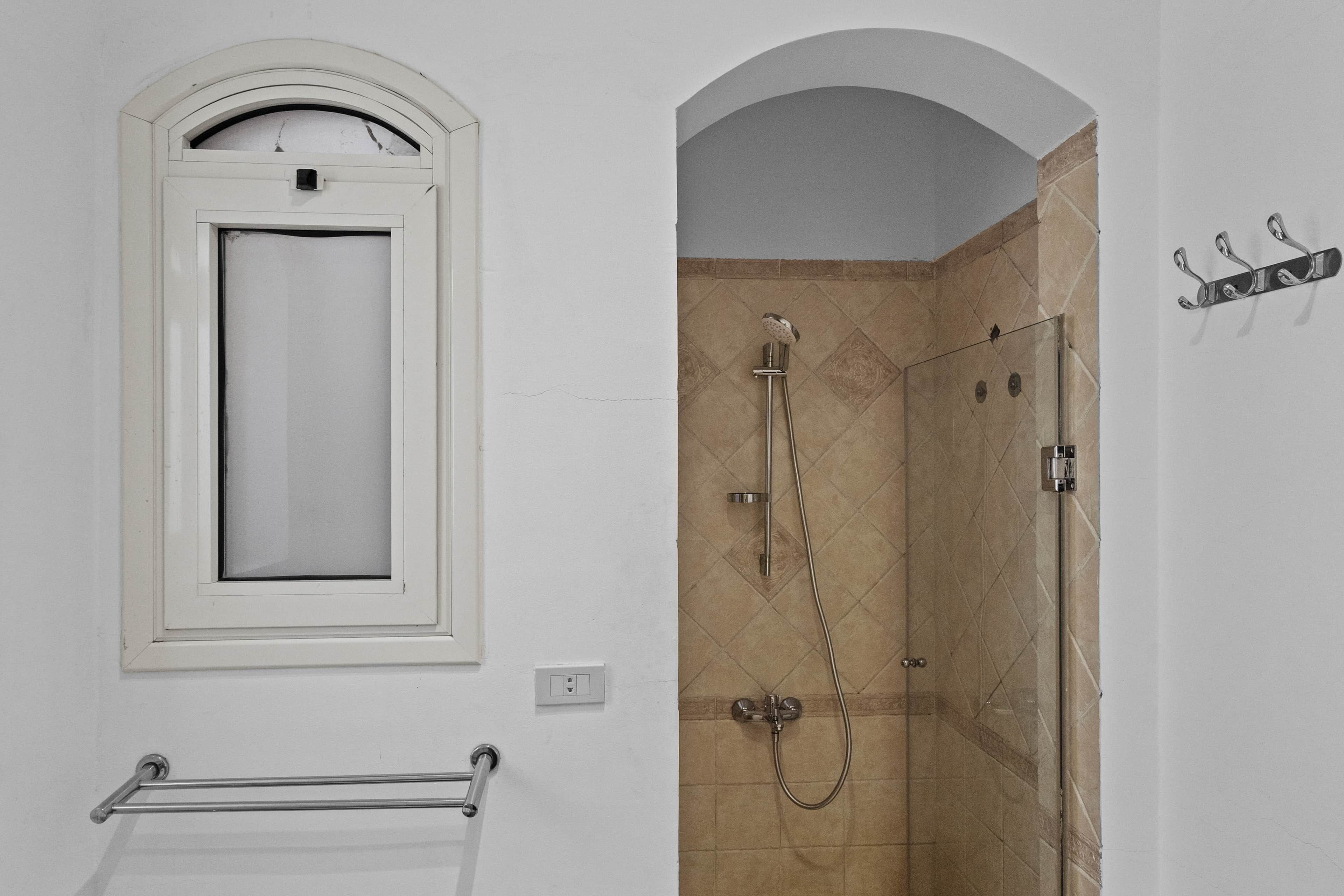 Ein Badezimmer mit Dusche, Handtuchhalter und einem Fenster.